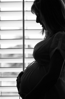Silhoette in profile of an expectant mother in front of bright w