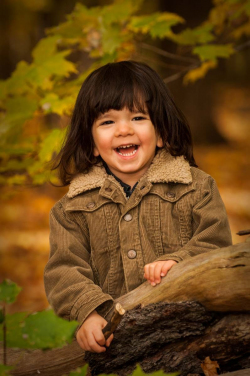 Outdoor portrait of a young boy with shoulder length hair wearin