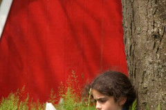 Young girl sitting on the ground in tall grass leaning against a
